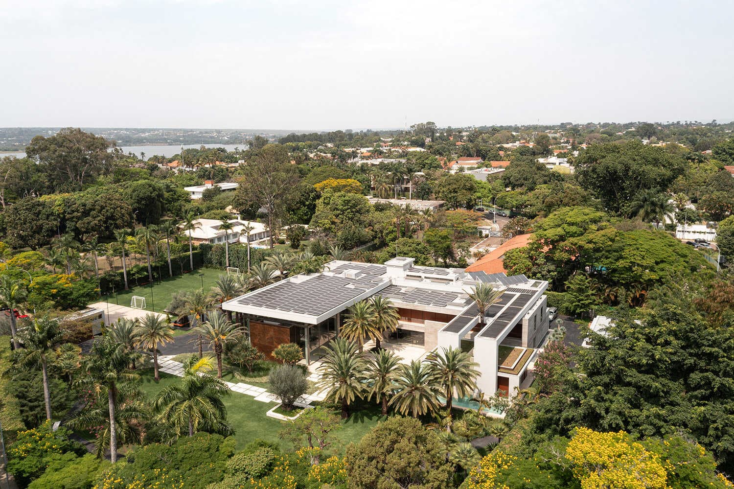 Vista aérea da casa com telhado de placas solares entre árvores