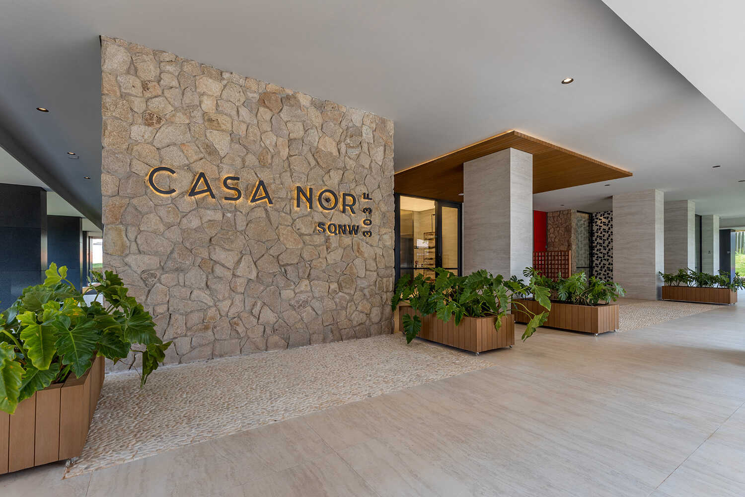 Lobby do Casa Nor com parede de pedra e letreiro iluminado