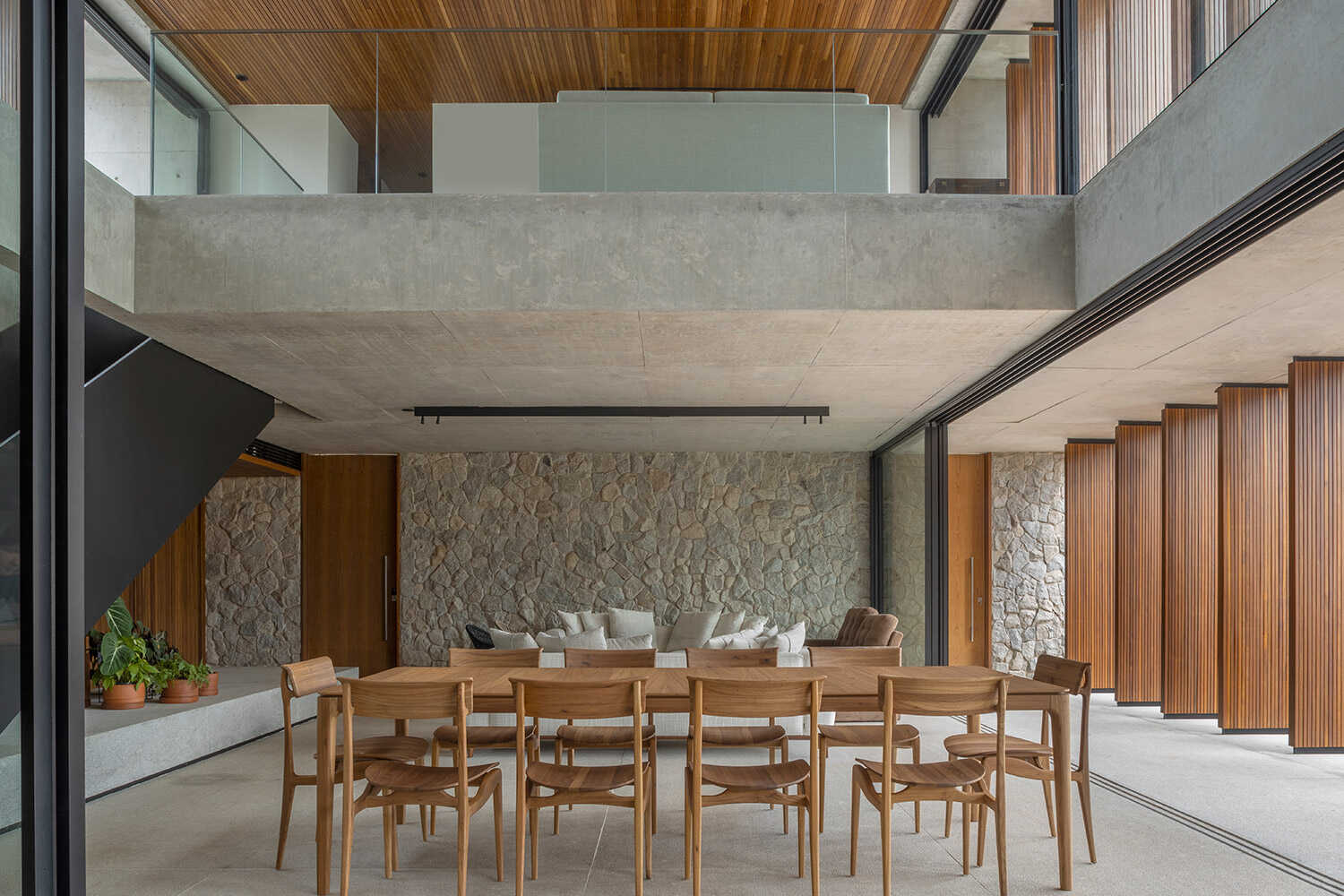 Sala de jantar em pé-direito duplo com parede de pedra