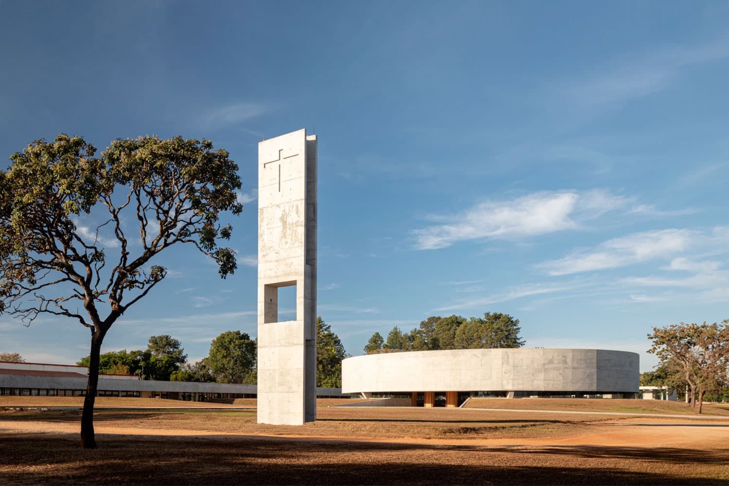Campanário de concreto com cruz e a nave circular
